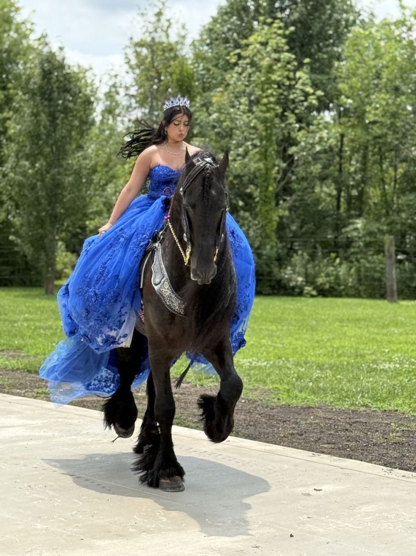 Quinceañera montando a caballo con vestido azul